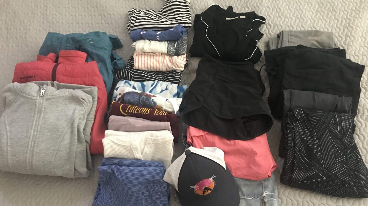 various jackets, pants, shirts and other articles of clothing laid out for a comprehensive packing guide for a national parks roadtrip