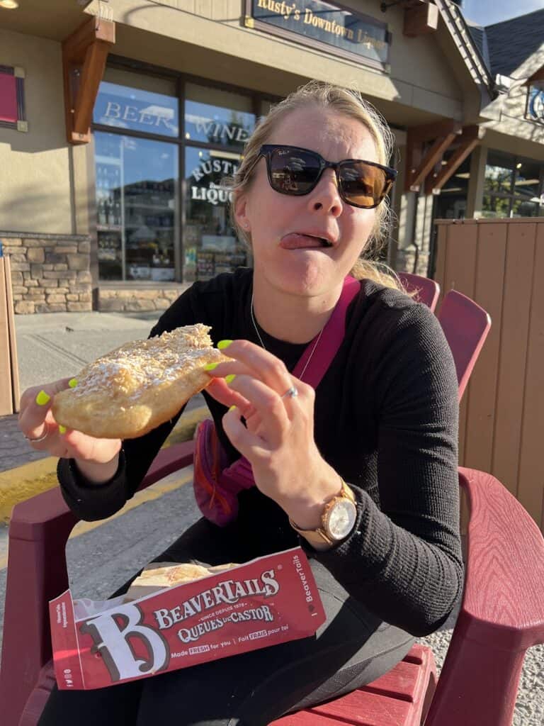 the author licks the maple sugar from her lips after taking a large bite of a beaver tail pastry in Banff 