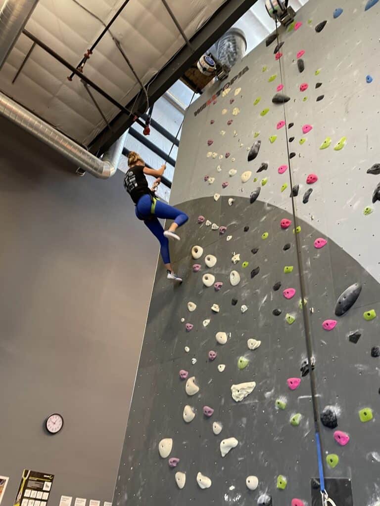 the author rappelling down a rock wall at an indoor rock climbing gym