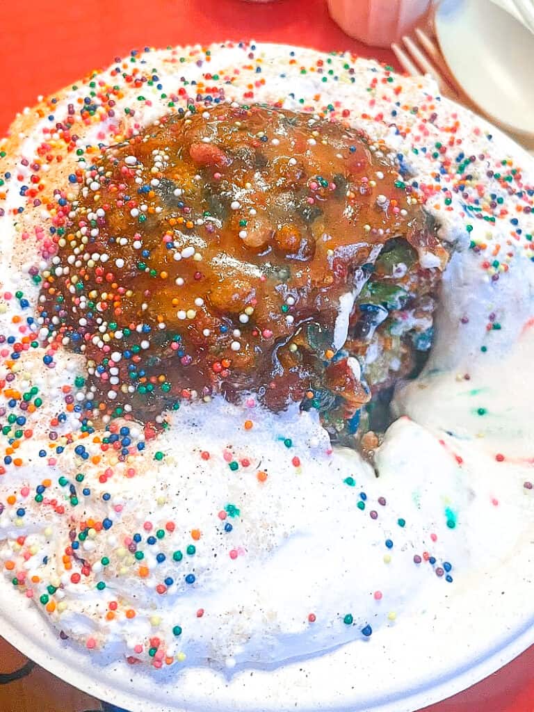 a closeup of fried ice cream from Unicorn Bar. A mound of ice cream, coated in fruity pebbles and topped with tons of whipped cream and sprinkles
