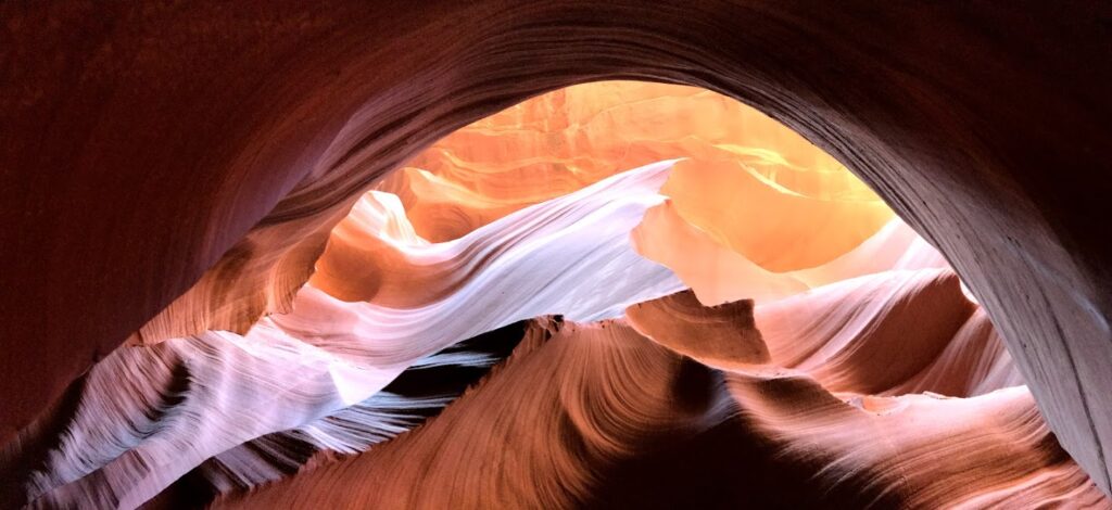 the walls of Antelope Canyon creating an image of mountains with a setting sun over them 