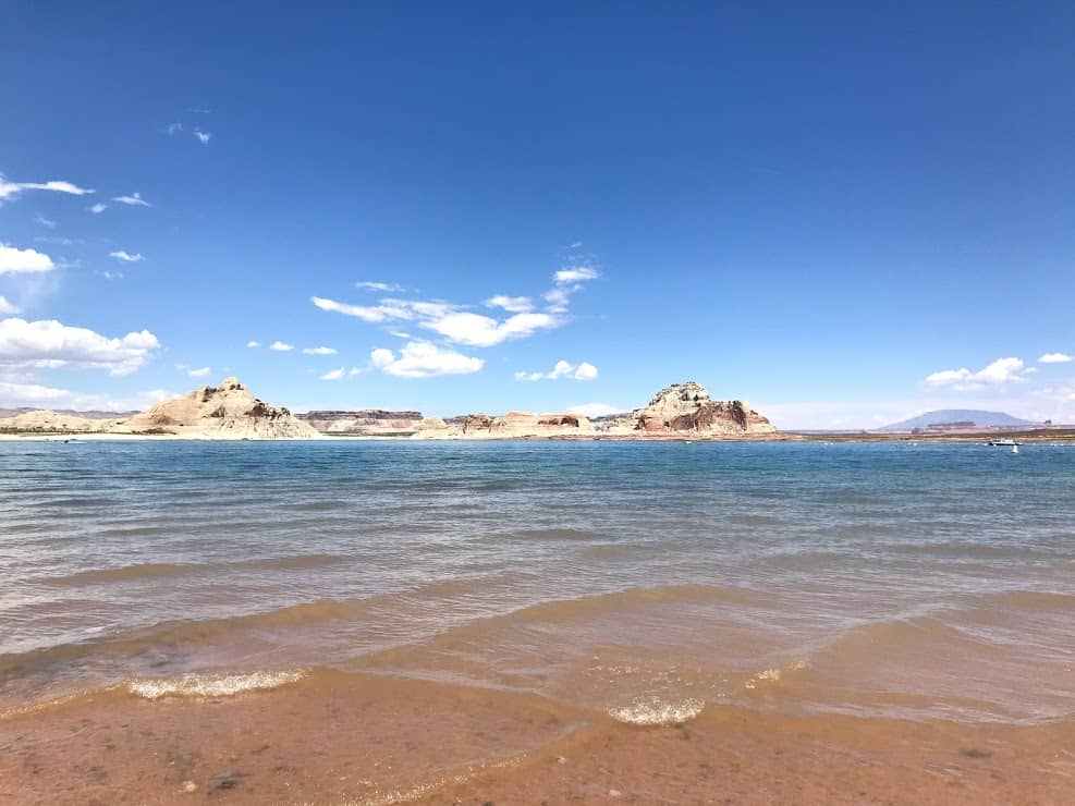 Large white rocks at Lake Powell sit in the background with the blue waters of Lake Powell in front 