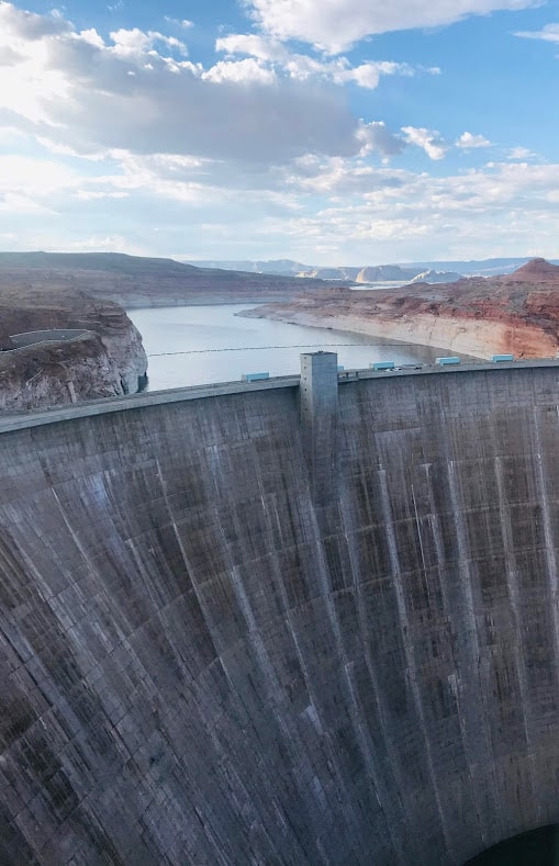 view of the sloping walls of concrete of the Glen Canyon Dam with Lake Powell sitting above it 