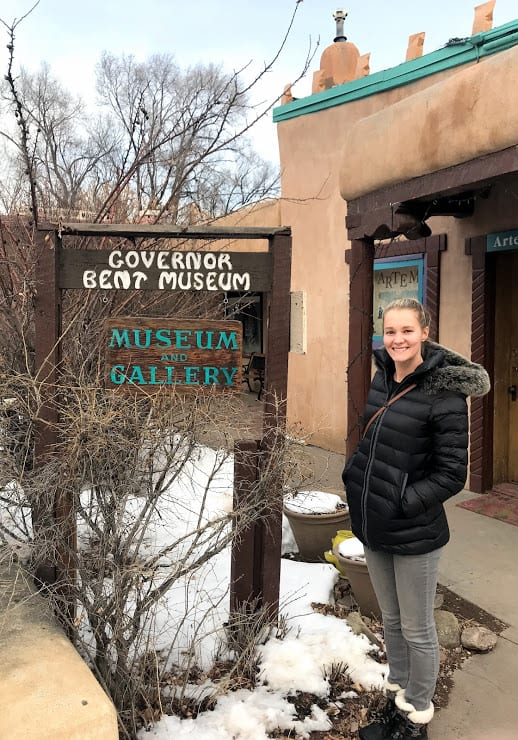 A blonde woman (me) stands in front of a sign that reads "Governor Bent Museum and Gallery"