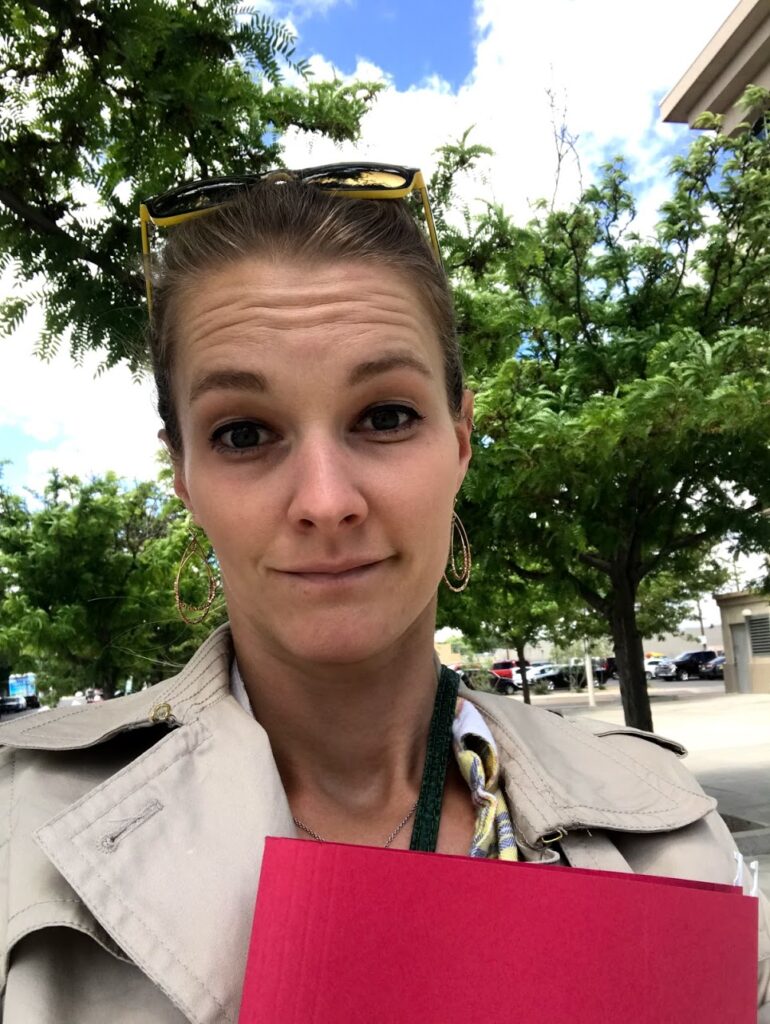 a woman holding a red file folder outside on a sunny day