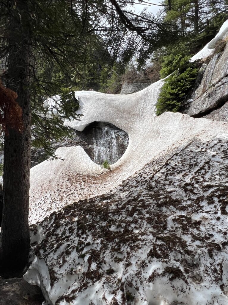 a snow covered waterfall flowing from Lake Agnes in Banff, Canada