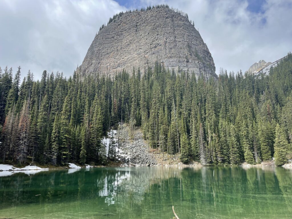 Mirror Lake looks green with a large rock structure in the background