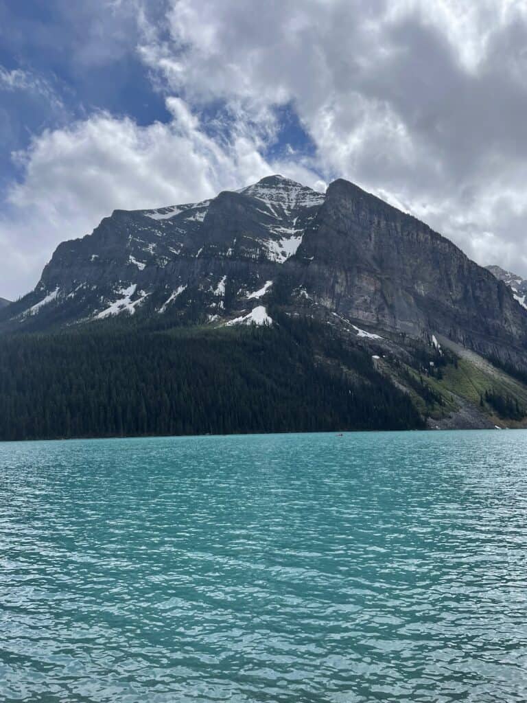 a mountain towers over the green waters of Lake Louise