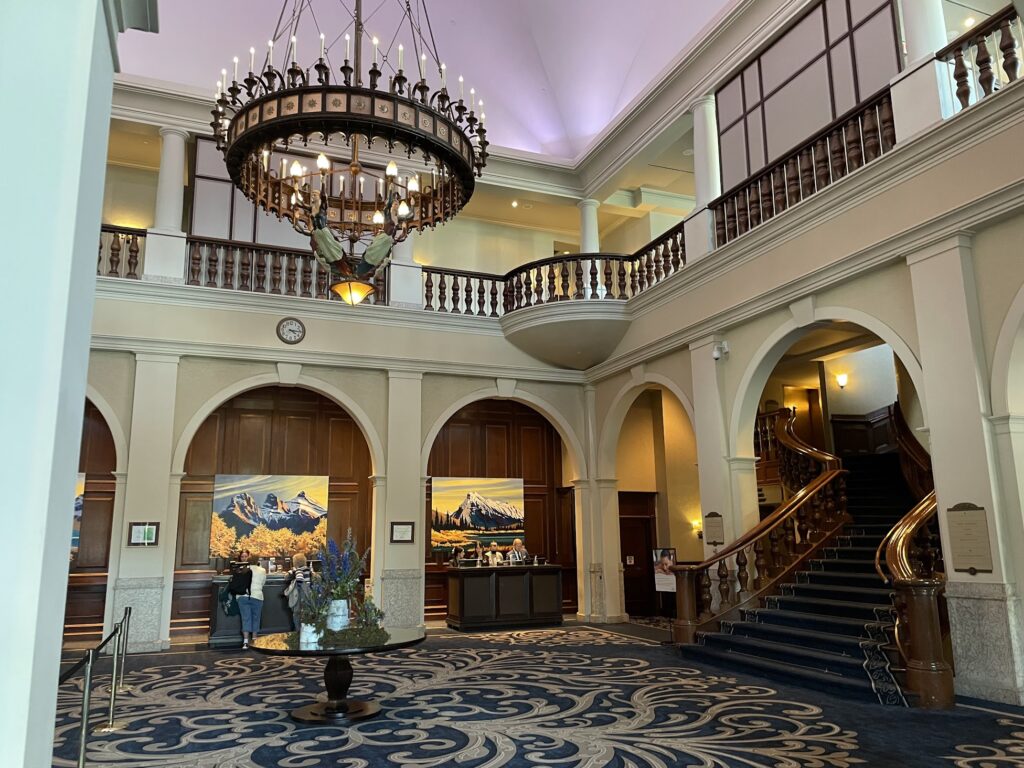 ornate carpets, a sweeping wooden staircase, and an elaborate chandelier decorate the lobby of the Fairmont Chateau