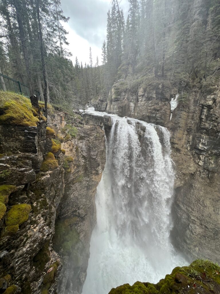 a large cascade of water tumbles down the Upper Falls of Johnston Canyon