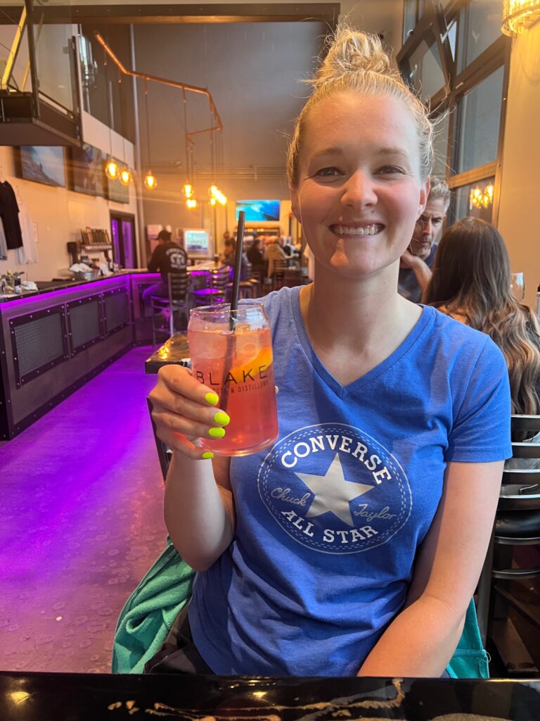 the author is smiling and holding a pink drink at The Blake in Canmore