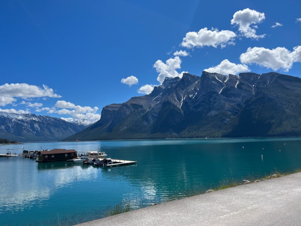 Lake Minnewanka, Banff. A boat dock is floating on the turquoise lake reflecting the blue sky 
