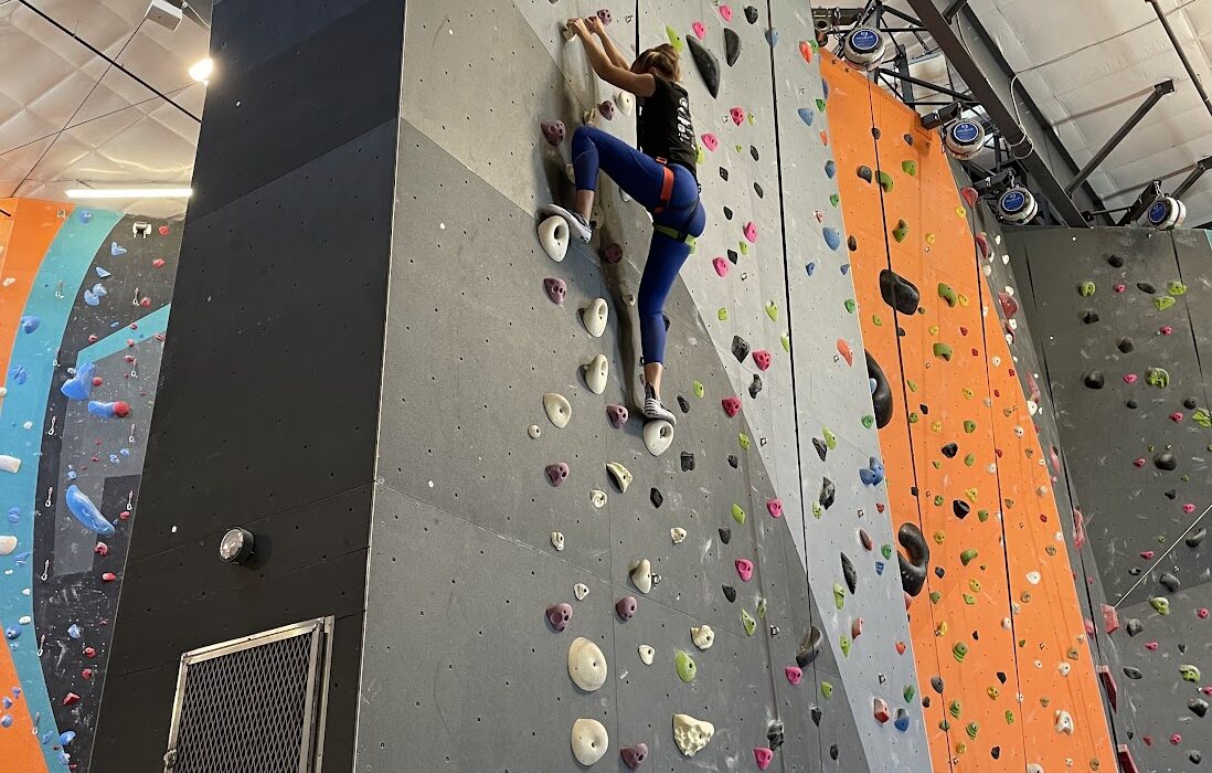 a woman climbing a rock wall in an indoor rock climbing gym