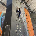 a woman climbing a rock wall in an indoor rock climbing gym