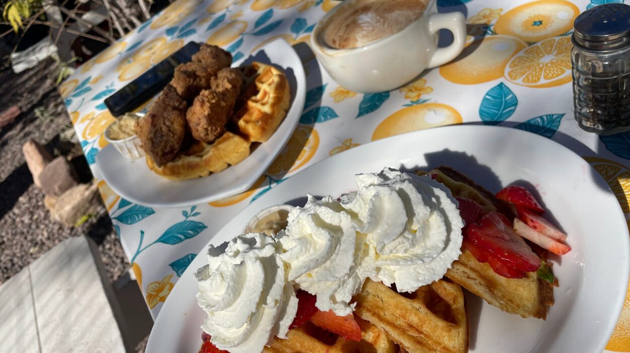 a plate of waffles and strawberries piled with whipped cream and at one of the best breakfast spots in Albuquerque: Tia B's waffleria