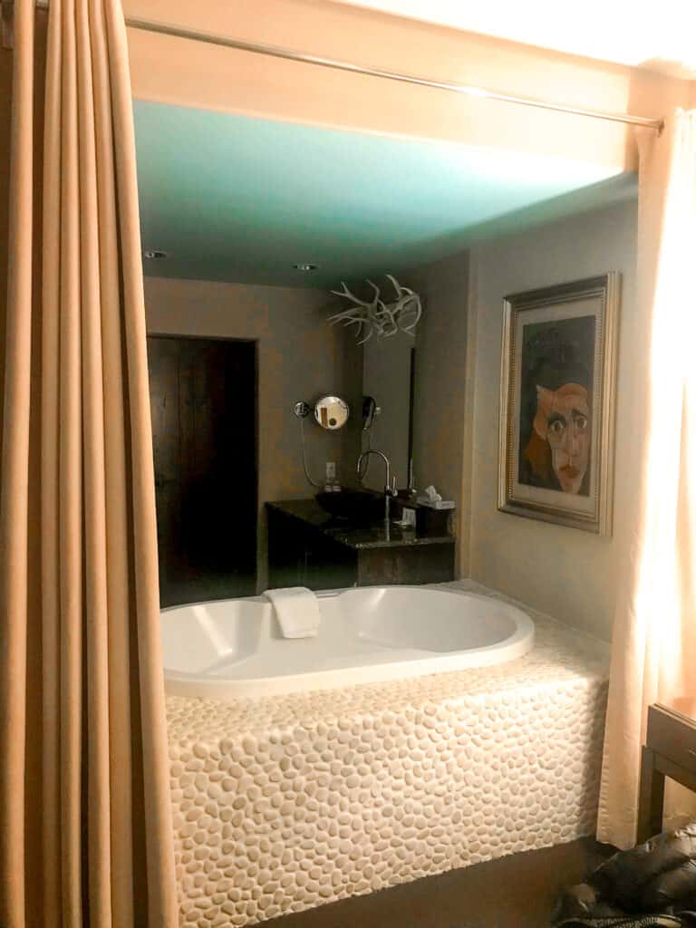 a white stone soaking tub flanked by curtains in the Taos Mountain room at El Monte Sagrado 