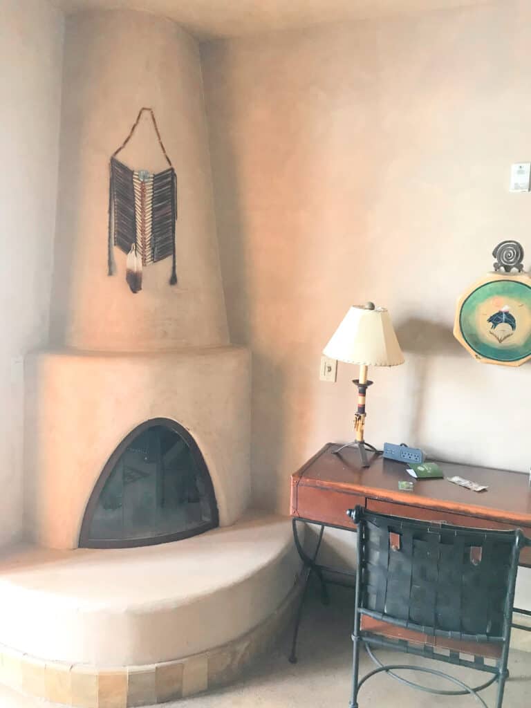 kiva fireplace ext to a wooden desk with an iron chair in Native American suites at El Monte Sagrado in Taos 