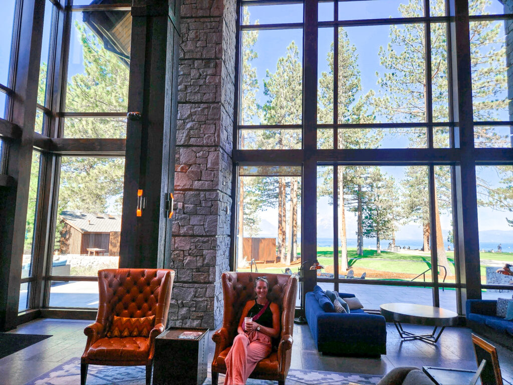 the author sits in a leather chair in front of a huge picture window showing a view of Lake Tahoe 